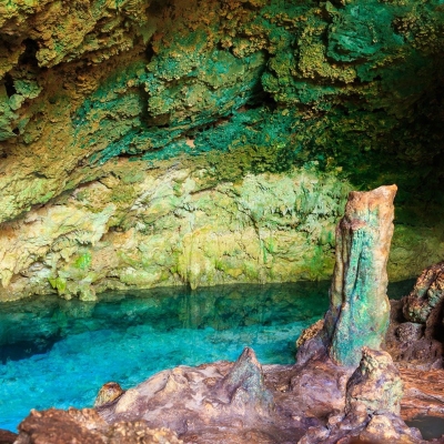 View of beautiful natural pool of crystal clear water formed in a rocky cave with stalagmites and stalagmites. Kuza cave in Zanzibar, Tanzania